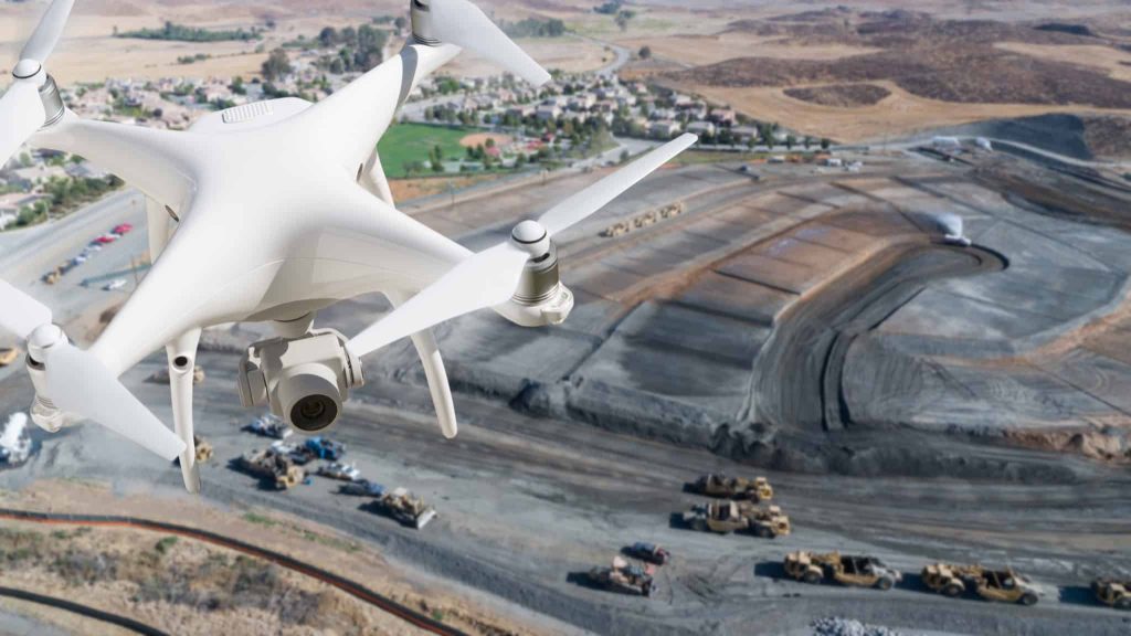 Close-up of a flying drone over a quarry site in the background.