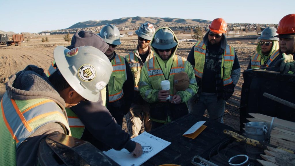 Fiore site workers stood around a table looking at site plans.