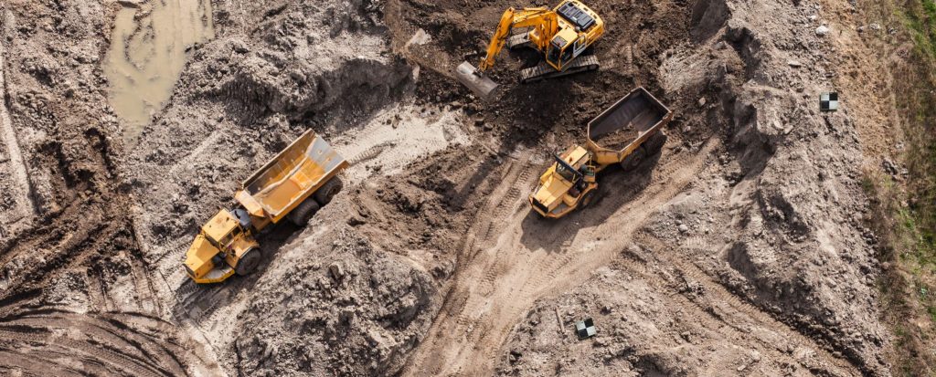Overhead photo of a construction site showing two trucks and a digger.