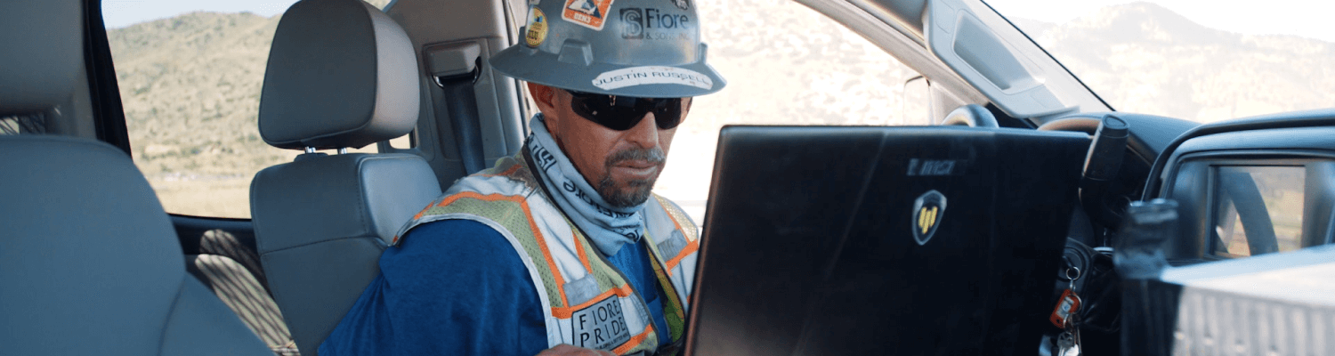 Construction worker using a laptop in a truck cab to access data via API integration
