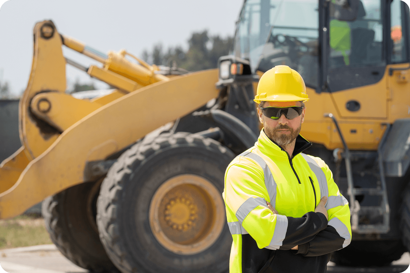 VP/owner on a construction site standing in front of a wheel loader